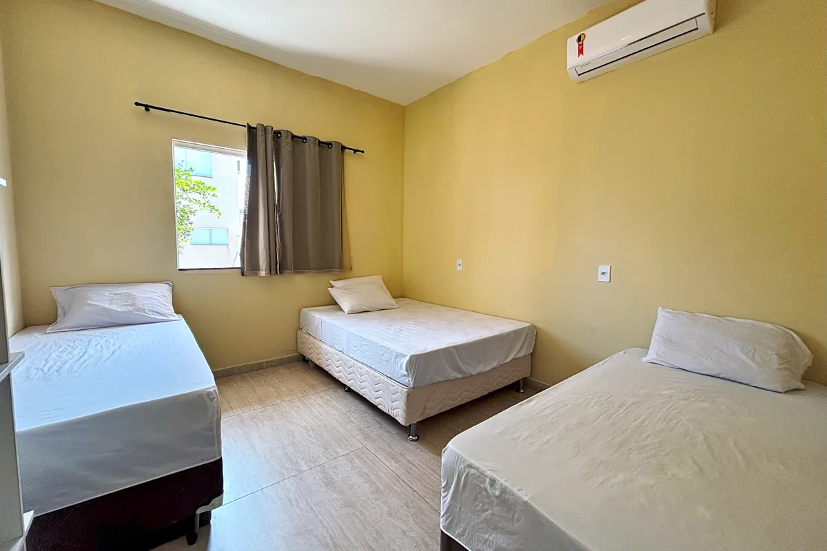 Quarto com três camas ar-condicionado e janela