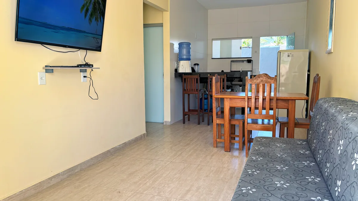 Sala de estar e jantar integradas com sofa, TV e cozinha americana ao fundo