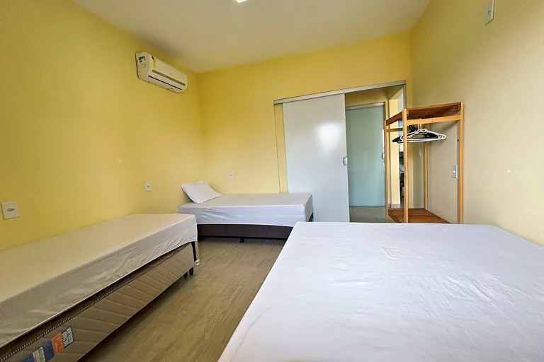 Quarto com cama de casal e solteiro ar condicionado split e closet aberto