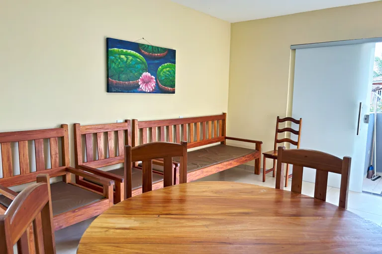 Sala de convivencia com bancos de madeira macica e mesa redonda