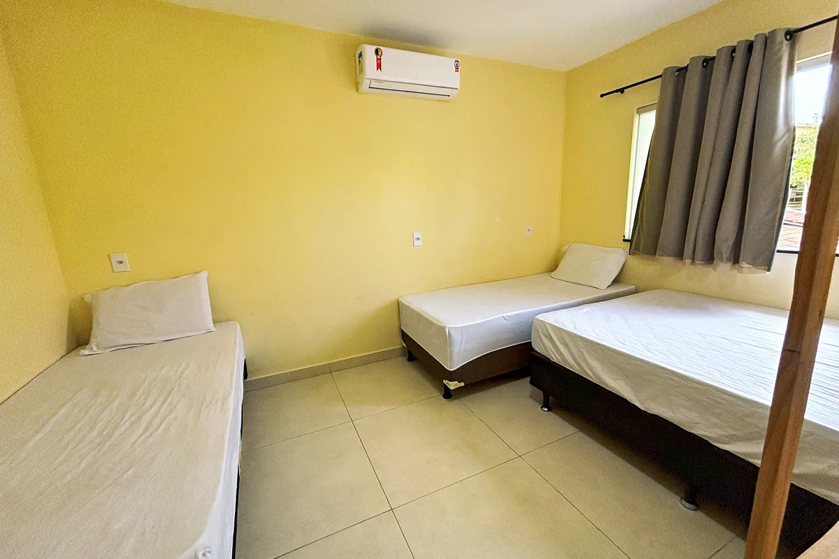 Quarto com três camas de solteiro ar condicionado split e cortina blackout