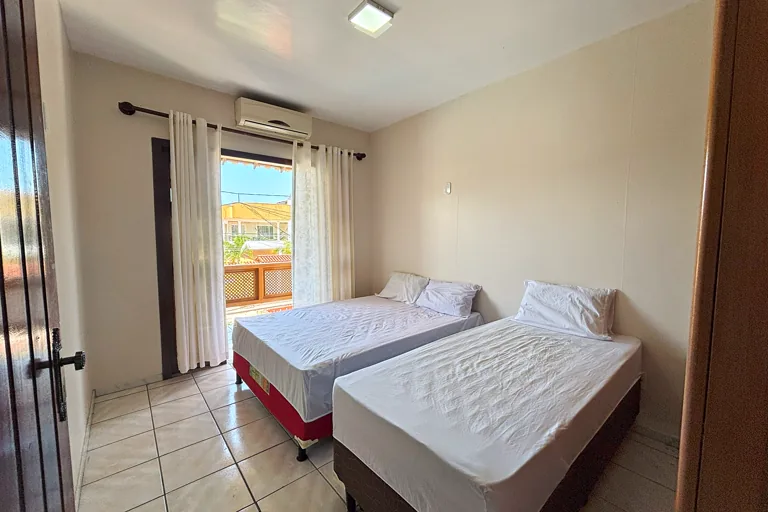 Quarto com cama de casal e cama de solteiro ar condicionado e porta para varanda