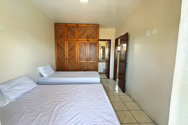Quarto com duas camas armario de madeira e porta para banheiro privativo