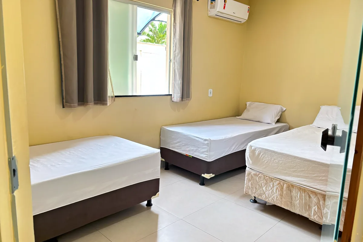 Quarto amplo com três camas e ar-condicionado split