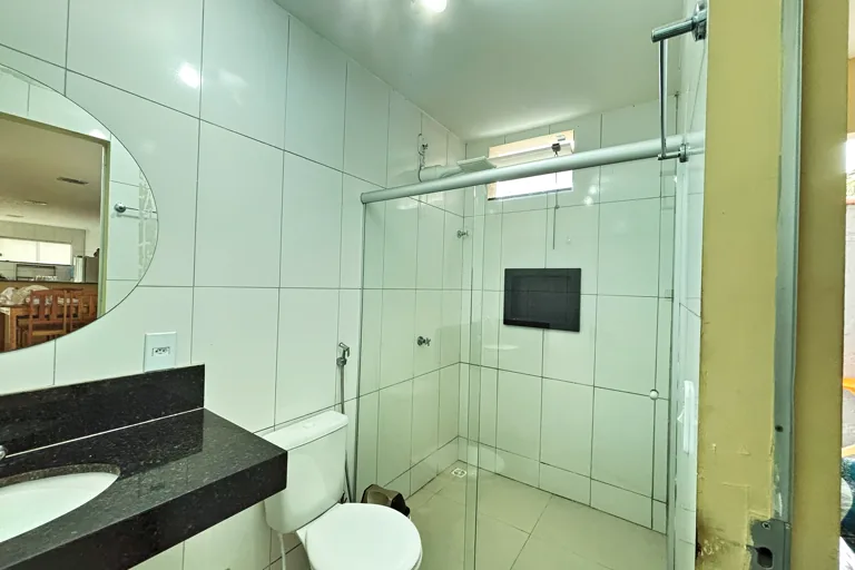 Banheiro com bancada de granito, espelho e box de vidro