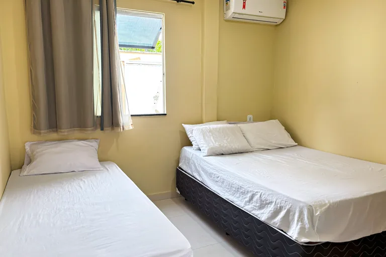 Quarto com cama de casal e cama de solteiro com luz natural