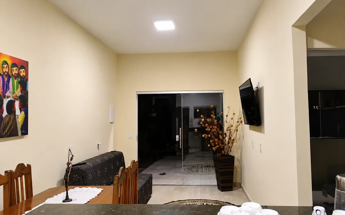 Sala de estar e jantar com sofa estampado, mesa de madeira e TV na parede.