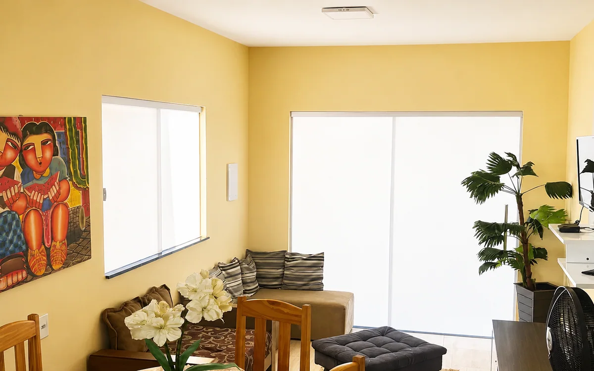 Sala de estar e jantar com mesa redonda, sofa e TV na parede.
