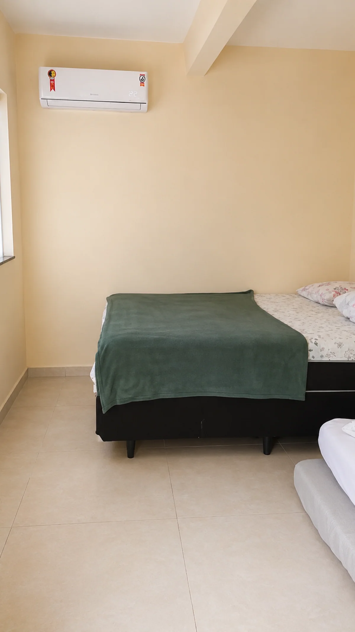 Quarto com camas de solteiro, cama de casal parcialmente visivel e ar-condicionado.