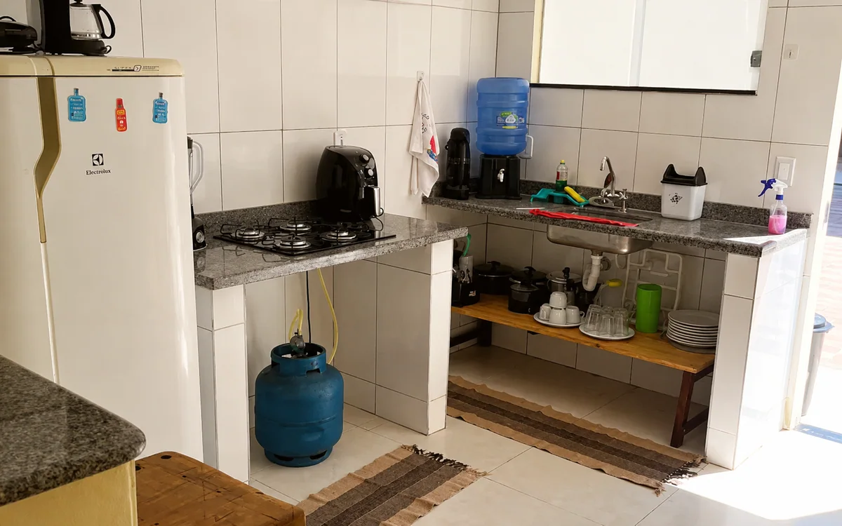 Cozinha com geladeira, cooktop, pia e bancada de granito.
