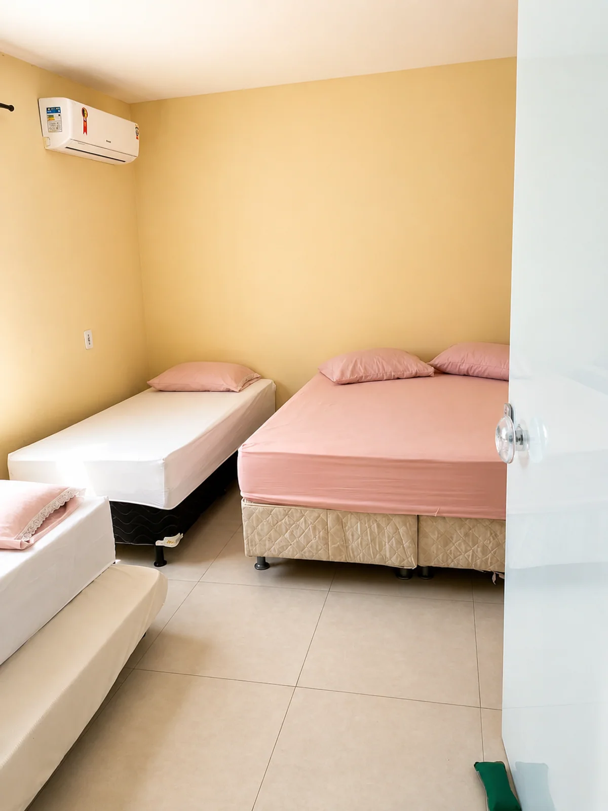 Quarto com cama de casal, cama de solteiro e ar-condicionado.